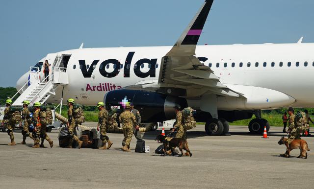Salvadorean military members with sniffer dogs prepare to board a plane heading to Venezuela, at Comalapa Air Base in San Luis Talpa, El Salvador, on June 25, 2026. A first plane carrying a 300-member team of rescuers and experts, as well as food supplies, was sent to Venezuela to assist after the devastating June 24 twin earthquakes. (Photo by Rudy QUIROZ / AFP)