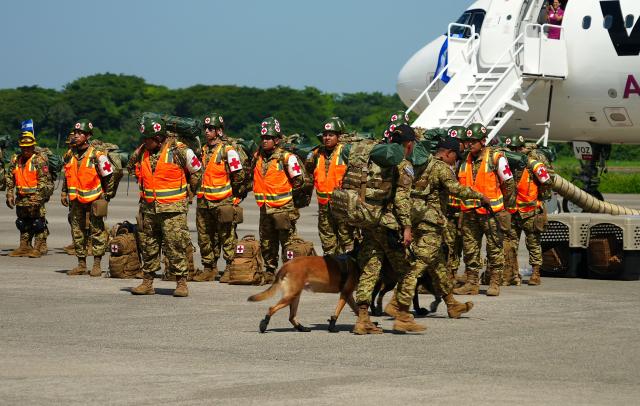 Salvadorean military members with sniffer dogs get ready to board a plane heading to Venezuela, at Comalapa Air Base in San Luis Talpa, El Salvador, on June 25, 2026. A first plane carrying a 300-member team of rescuers and experts, as well as food supplies, was sent to Venezuela to assist after the devastating June 24 twin earthquakes. (Photo by Rudy QUIROZ / AFP)