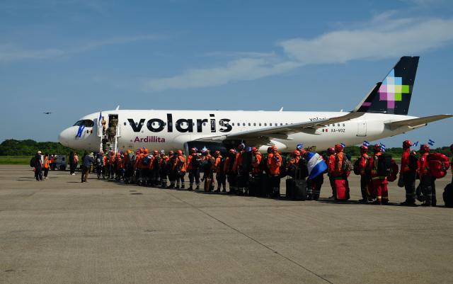 Salvadorean rescuers queue to board a plane heading to Venezuela, at Comalapa Air Base in San Luis Talpa, El Salvador, on June 25, 2026. A first plane carrying a 300-member team of rescuers and experts, as well as food supplies, was sent to Venezuela to assist after the devastating June 24 twin earthquakes. (Photo by Rudy QUIROZ / AFP)