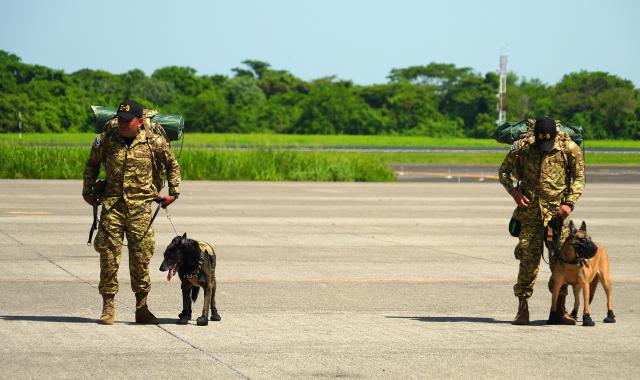 Salvadorean military members with sniffer dogs prepare to board a plane heading to Venezuela, at Comalapa Air Base in San Luis Talpa, El Salvador, on June 25, 2026. A first plane carrying a 300-member team of rescuers and experts, as well as food supplies, was sent to Venezuela to assist after the devastating June 24 twin earthquakes. (Photo by Rudy QUIROZ / AFP)