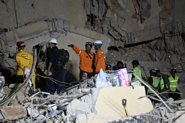 Rescue workers search through the rubble of a collapsed building in Caracas on June 25, 2026, following earthquakes. Desperate Venezuelans raced to find and rescue loved ones trapped alive beneath the rubble of collapsed buildings after two major earthquakes, measured at magnitudes 7.2 and 7.5, hit northern Venezuela killing at least 235 people and leaving more than 1,500 injured. (Photo by Juan BARRETO / AFP)