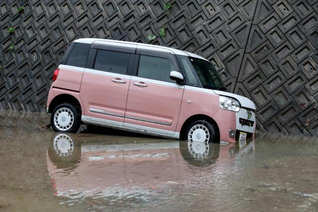 A partially submerged car is seen after flooding in the town of Kashiwara, Osaka prefecture on June 26, 2026. Japanese airlines cancelled more than 100 flights on june 26, as two tropical storms barrelled towards the archipelago, with authorities advising evacuations in some areas because of possible flooding and landslides. (Photo by PAUL MILLER / AFP)