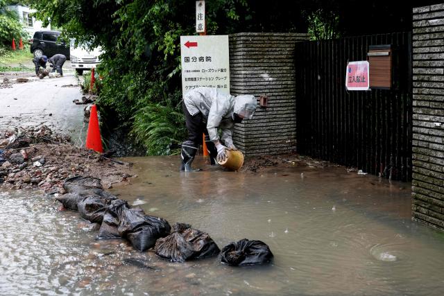 Residents clear debris after flooding in the town of Kashiwara, Osaka prefecture on June 26, 2026. Japanese airlines cancelled more than 100 flights on june 26, as two tropical storms barrelled towards the archipelago, with authorities advising evacuations in some areas because of possible flooding and landslides. (Photo by PAUL MILLER / AFP)