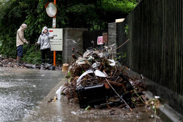 Residents clear debris after flooding in the town of Kashiwara, Osaka prefecture on June 26, 2026. Japanese airlines cancelled more than 100 flights on june 26, as two tropical storms barrelled towards the archipelago, with authorities advising evacuations in some areas because of possible flooding and landslides. (Photo by PAUL MILLER / AFP)