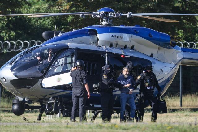 TOPSHOT - Judicial officers escort Saudi Arabian defendant Taleb Al Abdulmohsen upon his arrival by helicopter on June 26, 2026 in Magdeburg, eastern Germany, before his trial for driving an SUV through a Christmas market in a rampage on December 20, 2024, that killed a nine-year-old boy and five women aged between 45 and 75. The court is set to hand down its verdict June 26, 2026 for the Saudi psychiatrist who drove an SUV through a crowded Christmas market on December 20, 2024, killing six people and injuring more than 300. Prosecutors have sought a sentence of life in jail for Taleb Jawad al-Abdulmohsen, 51, and a ruling on the "particular gravity" of the crime that would help ensure he stays behind bars for the rest of his days. (Photo by Ronny HARTMANN / AFP)
