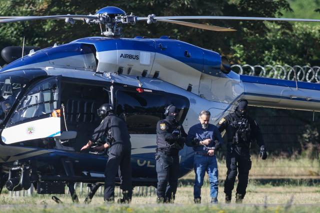 Judicial officers escort Saudi Arabian defendant Taleb Al Abdulmohsen upon his arrival by helicopter on June 26, 2026 in Magdeburg, eastern Germany, before his trial for driving an SUV through a Christmas market in a rampage on December 20, 2024, that killed a nine-year-old boy and five women aged between 45 and 75. The court is set to hand down its verdict June 26, 2026 for the Saudi psychiatrist who drove an SUV through a crowded Christmas market on December 20, 2024, killing six people and injuring more than 300. Prosecutors have sought a sentence of life in jail for Taleb Jawad al-Abdulmohsen, 51, and a ruling on the "particular gravity" of the crime that would help ensure he stays behind bars for the rest of his days. (Photo by Ronny HARTMANN / AFP)