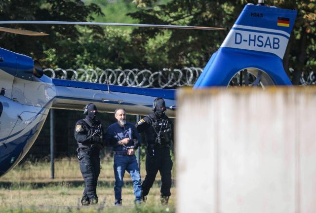 Judicial officers escort Saudi Arabian defendant Taleb Al Abdulmohsen upon his arrival by helicopter on June 26, 2026 in Magdeburg, eastern Germany, before his trial for driving an SUV through a Christmas market in a rampage on December 20, 2024, that killed a nine-year-old boy and five women aged between 45 and 75. The court is set to hand down its verdict June 26, 2026 for the Saudi psychiatrist who drove an SUV through a crowded Christmas market on December 20, 2024, killing six people and injuring more than 300. Prosecutors have sought a sentence of life in jail for Taleb Jawad al-Abdulmohsen, 51, and a ruling on the "particular gravity" of the crime that would help ensure he stays behind bars for the rest of his days. (Photo by Ronny HARTMANN / AFP)