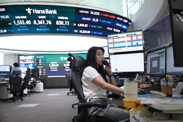 A currency dealer talks on the phone as she monitors exchange rates in a foreign exchange dealing room at the Hana Bank headquarters in Seoul on June 26, 2026. South Korean stocks collapsed more than eight percent on June 26, sparking a 20 minute halt in trading, amid a fresh rout in tech firms and following a sell-off on Wall Street. (Photo by Jung Yeon-je / AFP)