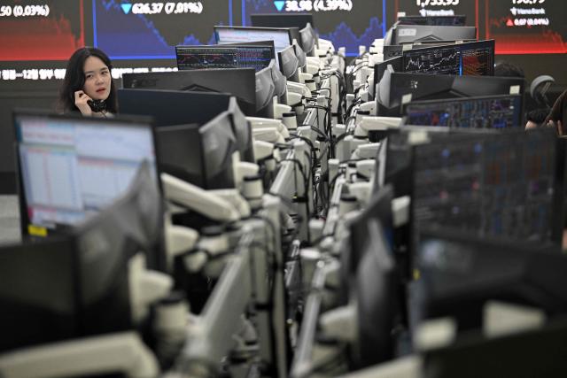 A currency dealer talks on the phone as she monitors exchange rates in a foreign exchange dealing room at the Hana Bank headquarters in Seoul on June 26, 2026. South Korean stocks collapsed more than eight percent on June 26, sparking a 20 minute halt in trading, amid a fresh rout in tech firms and following a sell-off on Wall Street. (Photo by Jung Yeon-je / AFP)