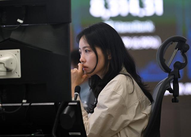 A currency dealer monitors exchange rates in a foreign exchange dealing room at the Hana Bank headquarters in Seoul on June 26, 2026. South Korean stocks collapsed more than eight percent on June 26, sparking a 20 minute halt in trading, amid a fresh rout in tech firms and following a sell-off on Wall Street. (Photo by Jung Yeon-je / AFP)