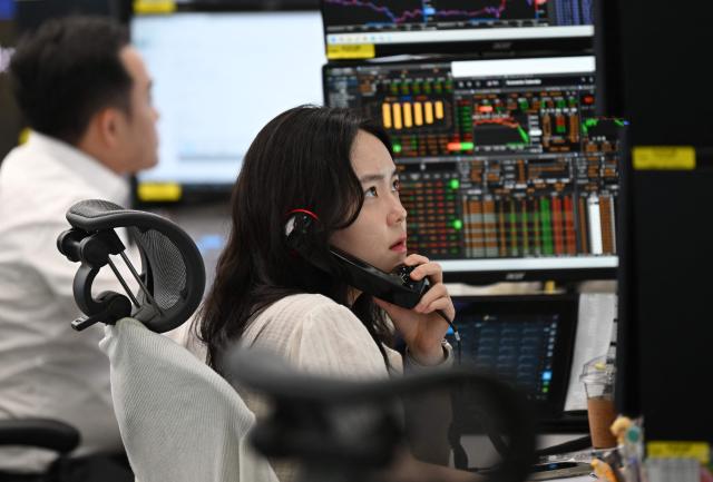 A currency dealer talks on the phone as she monitors exchange rates in a foreign exchange dealing room at the Hana Bank headquarters in Seoul on June 26, 2026. South Korean stocks collapsed more than eight percent on June 26, sparking a 20 minute halt in trading, amid a fresh rout in tech firms and following a sell-off on Wall Street. (Photo by Jung Yeon-je / AFP)