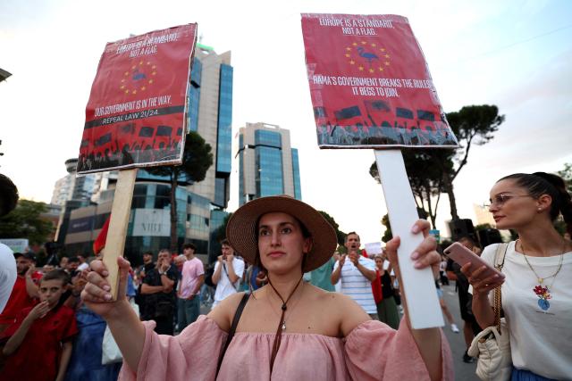 Protestors hold placards as they gather outside Albania's Prime Minister's office to oppose the construction of luxury resorts, in Tirana on June 25, 2026. Since late May 2026 protesters have thronged the streets every evening to oppose plans to build a luxury seaside resort at Zvernec, in a protected area, and on Sazan island, both in south-western Albania — valued at more than four billion euros and linked to Donald Trump's daughter Ivanka and her husband Jared Kushner. (Photo by Adnan Beci / AFP)