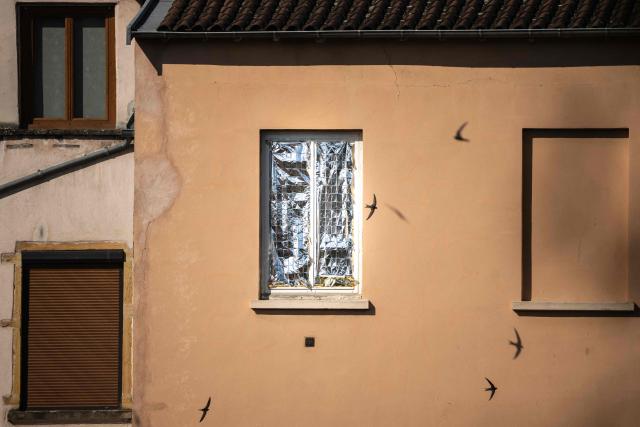 Birds fly past a window hidden by an emergency blanket during a heatwave in Lyon, central-eastern France on June 26, 2026. A deadly European heatwave that has saturated hospitals as temperatures soared to record highs was to shift east on June 26, 2026, with authorities warning of more misery on a continent not used to stretches of punishing heat. (Photo by OLIVIER CHASSIGNOLE / AFP)