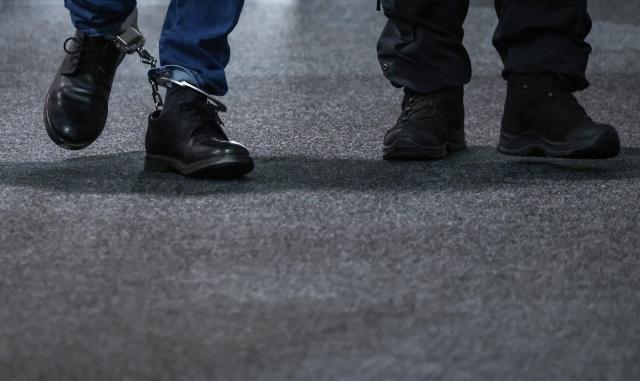 Saudi Arabian defendant Taleb Jawad al-Abdulmohsen (L) wears ankle cuffs as he is led by judicial officers to the temporary courtroom in Magdeburg, eastern Germany on June 26, 2026, before his trial for driving an SUV through a crowd at a Christmas market. The court sentenced to life in jail the Saudi psychiatrist who drove an SUV through a crowded Christmas market in 2024, killing six people and injuring more than 300. (Photo by Ronny HARTMANN / AFP)