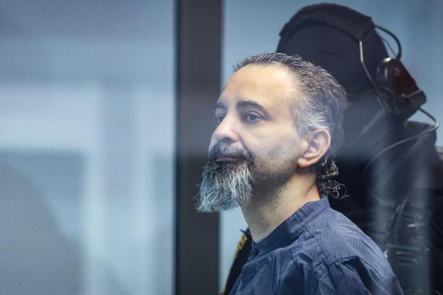 Saudi Arabian defendant Taleb Jawad al-Abdulmohsen (L) stands next to a judicial security officer as he waits inside a bulletproof glass box in the temporary courtroom in Magdeburg, eastern Germany, before his trial for driving an SUV through a crowd at a Christmas market. The court sentenced to life in jail the Saudi psychiatrist who drove an SUV through a crowded Christmas market in 2024, killing six people and injuring more than 300. (Photo by Ronny HARTMANN / AFP)