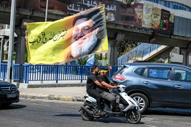 Men ride a scooter flying a banner depicting Hassan Nasrallah, the slain leader of the Lebanese Shia movement Hezbollah who was killed in a 2024 Israeli-airstrike, in Beirut’s southern suburbs on June 26, 2026 at the peak of Ashura, a 10-day period commemorating the seventh century killing of Prophet Mohammed's grandson Imam Hussein. (Photo by Joseph EID / AFP)