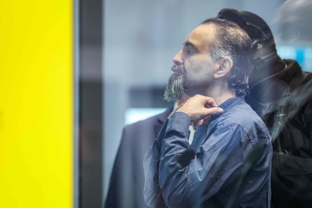 Saudi Arabian defendant Taleb Jawad al-Abdulmohsen (L) stands next to an judicial security officer as he waits inside a bulletproof glass box in the temporary courtroom in Magdeburg, eastern Germany, before his trial for driving an SUV through a crowd at a Christmas market. The court sentenced to life in jail the Saudi psychiatrist who drove an SUV through a crowded Christmas market in 2024, killing six people and injuring more than 300. (Photo by Ronny HARTMANN / AFP)