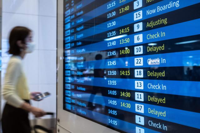 Screens show delayed flights in the departure hall of Tokyo's Haneda Airport on June 26, 2026. Japanese airlines cancelled more than 100 flights on June 26 as two tropical storms barrelled towards the archipelago, with authorities advising evacuations in some areas because of possible flooding and landslides. (Photo by Philip FONG / AFP)