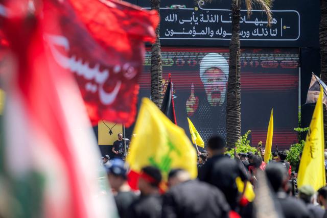 A crowd of Shia Muslim devotees watches as a televised speech by Naim Qassem, leader of Lebanese Shia movement Hezbollah, is displayed on a screen during a religious mourning event in Beirut’s southern suburbs on June 26, 2026 at the peak of Ashura, a 10-day period commemorating the seventh century killing of Prophet Mohammed's grandson Imam Hussein. (Photo by ibrahim AMRO / AFP)