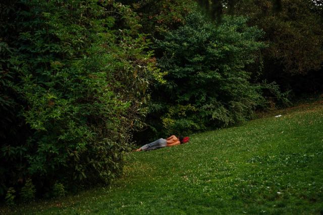 A man rests while sheltering from the heat in the Parc des Buttes-Chaumont in Paris, early June 26, 2026, as France experiences a heatwave. Hundreds of Parisians seeking relief from the heat took refuge in the Parc des Buttes-Chaumont, in the north-east of the capital, which has remained open round the clock throughout the heatwave affecting France. (Photo by Dimitar DILKOFF / AFP)