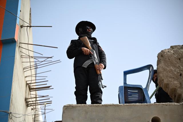 A Taliban security personnel stands guard on a rooftop, on the tenth day of Ashura during the Islamic holy month of Muharram in Kandahar on June 26, 2026. (Photo by Sanaullah SEIAM / AFP)