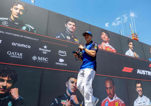 Red Bull Racing's French driver Isack Hadjar walks past a wall with portraits of current F1 drivers as he arrives to the paddock prior to the first practice session at the Red Bull Ring race track in Spielberg, Austria on June 26, 2026, ahead of the Formula One Austrian Grand Prix. (Photo by Joe KLAMAR / AFP)