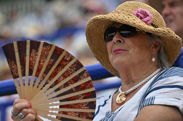 A spectator uses a fan to cool themself from the heat, during a heatwave, at on day five of the Lexus Eastbourne Open at Devonshire Park, Eastbourne, on the south coast of England on June 26, 2026. (Photo by Glyn KIRK / AFP)