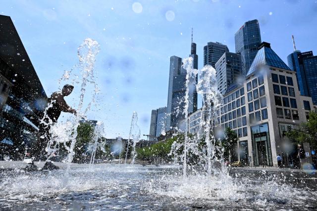 A man cools himself in a fountain outside the banking district in central Frankfurt am Main, western Germany, on June 26, 2026 with air temperature reaching 39 degrees Celsius. A heatwave sweeping Europe was starting to peak in Germany, with several open-air events cancelled and temperatures expected to top 40C through the weekend. Large parts of the country are already under "severe to extreme heat stress", the German Weather Service (DWD) said. (Photo by Kirill KUDRYAVTSEV / AFP)