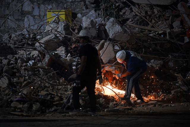 A rescuer cuts the steel bars of a collapsed building with an angle grinder in Caracas on June 25, 2026, following deadly earthquakes. Using heavy equipment or their bare hands, rescuers and volunteers searched for survivors of the twin earthquake in Venezuela, which has officially left 589 dead and, according to estimates, thousands missing. (Photo by Juan BARRETO / AFP)