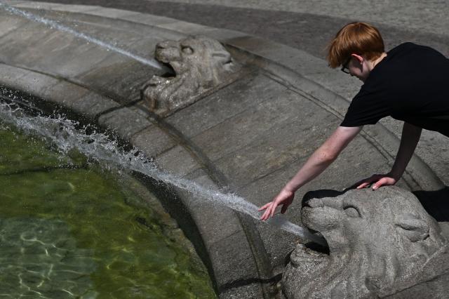 A boy cools off with water from a fountain as temperatures approach 32 degrees Celsius in Warsaw on June 26, 2026. (Photo by Sergei GAPON / AFP)