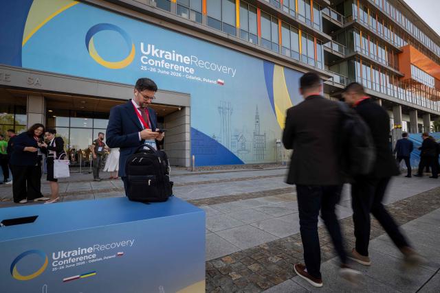 Visitors walk in front of the entrance of the Ukraine Recovery Conference (URC 2026) hosted by the Polish Prime Minister in Gdansk, Poland, on June 26, 2026. The Ukraine Recovery Conference (URC 2026), co-hosted by Poland and Ukraine, takes place in Gdansk on June 25–26, 2026, aiming to strengthen support for Ukraine’s reconstruction and boost investment, with a focus on energy, critical infrastructure, and logistics sectors. (Photo by Wojtek RADWANSKI / AFP)