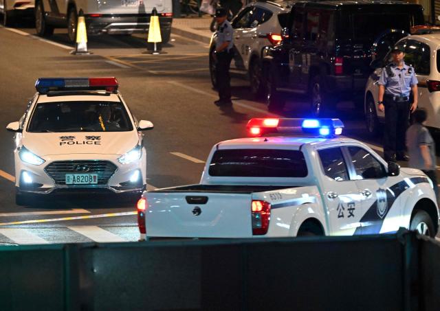 Police personnel block the road near the CITIC Tower in Beijing on June 26, 2026, after an eyewitness reported plane debris at the base of Beijing's tallest building. Video footage taken from a nearby building by the witness showed fire trucks blasting water at smoke billowing from the 528-metre (1,732-foot) CITIC Tower, while the wreck of a plane lay on the ground beside the building. (Photo by Adek BERRY / AFP)