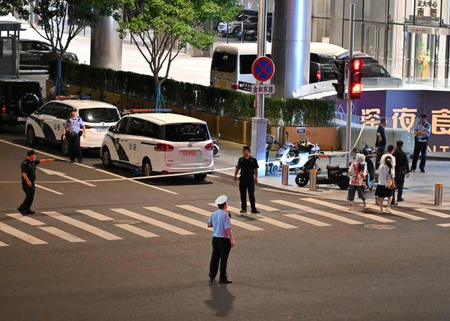 Police personnel block the road near the CITIC Tower in Beijing on June 26, 2026, after an eyewitness reported plane debris at the base of Beijing's tallest building. Video footage taken from a nearby building by the witness showed fire trucks blasting water at smoke billowing from the 528-metre (1,732-foot) CITIC Tower, while the wreck of a plane lay on the ground beside the building. (Photo by Adek BERRY / AFP)