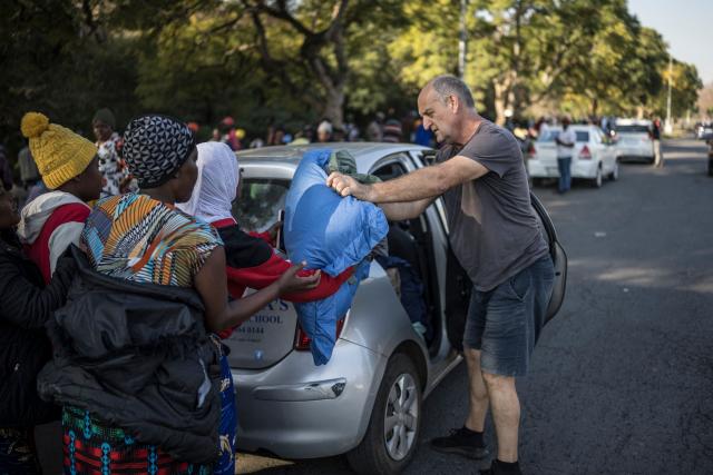 A South African man brings blankets and pillows to Malawian undocumented migrants hoping to board buses taking them back home at a temporary site along Mayor's Walk in Pietermaritzburg, on June 26, 2026. South Africans President Cyril Ramaphosa vowed on Thursday to crush any attempts to destabilise the nation during planned anti-immigrant marches next week, amid a wave of xenophobia.Citizen-led groups have set Tuesday 30 as a deadline for undocumented foreigners to leave and called for nationwide marches against illegal immigration, marking a crescendo in months of protests that have at times turned violent. (Photo by MARCO LONGARI / AFP)