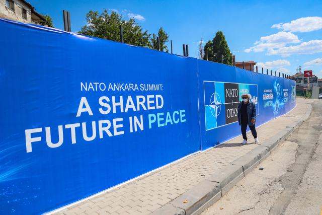 A local resident walks past billboards with the slogans “Key to Peace,” “Key to Security,” and “Shared Future in Peace”, displayed along the boulevard on the protocol route ahead of the NATO Summit in Ankara, on 26 June 2026. The 36th NATO summit will be held in Ankara on July 7-8, 2026. (Photo by ADEM ALTAN / AFP)