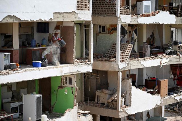 EDITORS NOTE: Graphic content / A man removes debris using a bucket inside a heavily damaged apartment in a partially collapsed building in Catia La Mar, La Guaira, Venezuela, on June 26, 2026, following earthquakes. The death toll from two powerful earthquakes that devastated Venezuela earlier this week rose to 920 on June 26, National Assembly President Jorge Rodriguez said. (Photo by Federico PARRA / AFP)