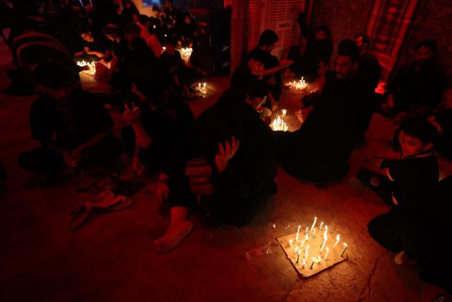Shiite Muslims light candles near the shrine of Imam Hussein during the traditional Tuwairij Run, as part of Ashura, a 10-day period commemorating the seventh century killing of Prophet Mohammed's grandson Imam Hussein, in the Iraqi holy city of Karbala, on July 26, 2026. (Photo by AHMAD AL-RUBAYE / AFP)