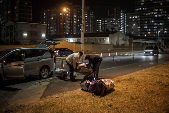 Undocumented migrants offload their belonging from a car before entering the gates of the old Durban Drive Inn where they will be registered by South African Immigration Officers ahead of their repatriation, in Durban on June 26, 2026. South Africa, one of Africa's largest and most industrialised economies, has been on edge following weeks of sometimes violent xenophobic unrest that has left at least two people dead. Small but organised groups have issued an ultimatum for undocumented migrants to exit or face consequences, a demand with no legal force. (Photo by MARCO LONGARI / AFP)