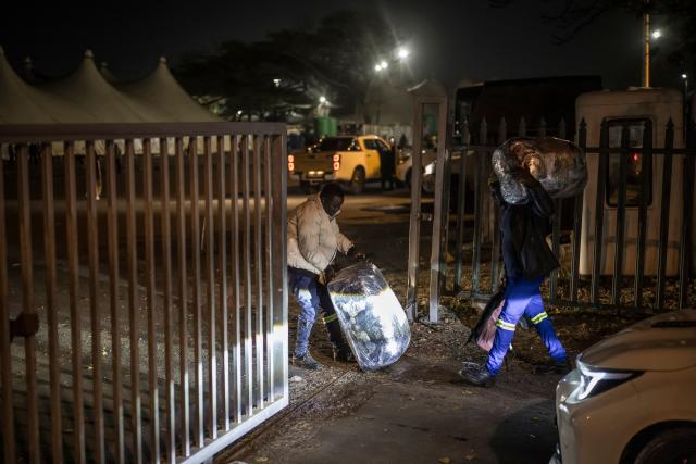 Undocumented migrants carry their belonging as they prepare to enter the gate of the old Durban Drive Inn where they will be registered by South African Immigration Officers ahead of their repatriation, in Durban on June 26, 2026. South Africa, one of Africa's largest and most industrialised economies, has been on edge following weeks of sometimes violent xenophobic unrest that has left at least two people dead. Small but organised groups have issued an ultimatum for undocumented migrants to exit or face consequences, a demand with no legal force. (Photo by MARCO LONGARI / AFP)