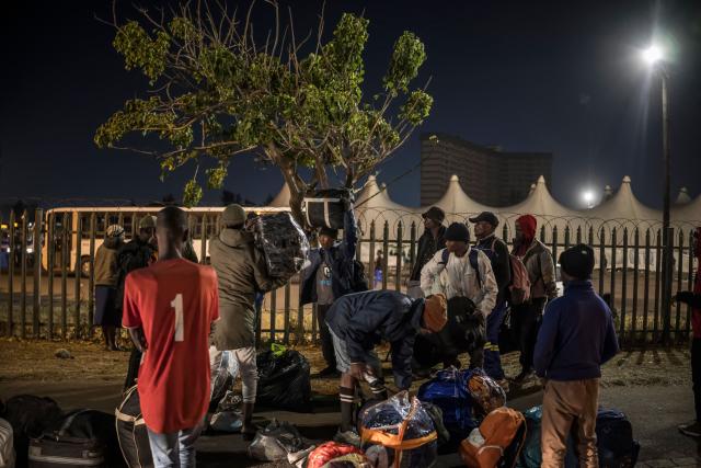 A group of undocumented migrants carry their belonging as they prepare to enter the gate of the old Durban Drive Inn where they will be registered by South African Immigration Officers ahead of their repatriation, in Durban on June 26, 2026. South Africa, one of Africa's largest and most industrialised economies, has been on edge following weeks of sometimes violent xenophobic unrest that has left at least two people dead. Small but organised groups have issued an ultimatum for undocumented migrants to exit or face consequences, a demand with no legal force. (Photo by MARCO LONGARI / AFP)