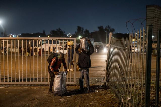 Undocumented migrants carry their belonging as they prepare to enter the gate of the old Durban Drive Inn where they will be registered by South African Immigration Officers ahead of their repatriation, in Durban on June 26, 2026. South Africa, one of Africa's largest and most industrialised economies, has been on edge following weeks of sometimes violent xenophobic unrest that has left at least two people dead. Small but organised groups have issued an ultimatum for undocumented migrants to exit or face consequences, a demand with no legal force. (Photo by MARCO LONGARI / AFP)