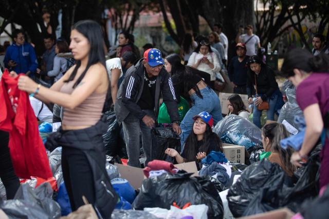 Volunteers sort and organize donated clothes and essential goods outdoors as humanitarian aid to be sent to Venezuela following deadly earthquakes, in Bogota on June 26, 2026. The death toll from two powerful earthquakes that devastated Venezuela earlier this week rose to 920 on June 26, National Assembly President Jorge Rodriguez said. (Photo by ESTEBAN VEGA LA-ROTTA / AFP)
