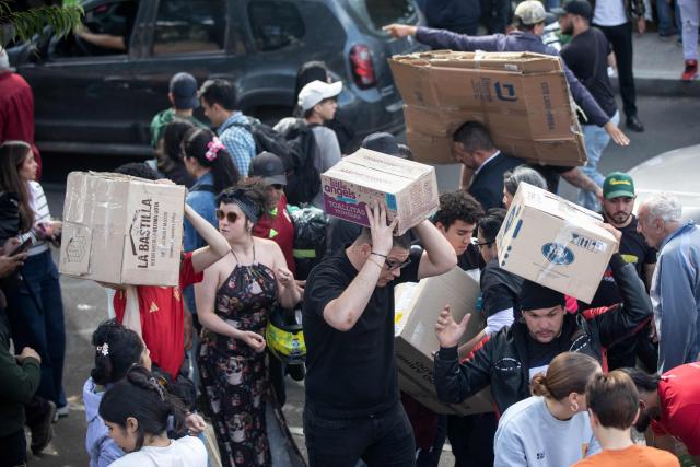 Volunteers carry boxes and other donated goods as humanitarian aid to be sent to Venezuela following deadly earthquakes, in Bogota on June 26, 2026. The death toll from two powerful earthquakes that devastated Venezuela earlier this week rose to 920 on June 26, National Assembly President Jorge Rodriguez said. (Photo by ESTEBAN VEGA LA-ROTTA / AFP)