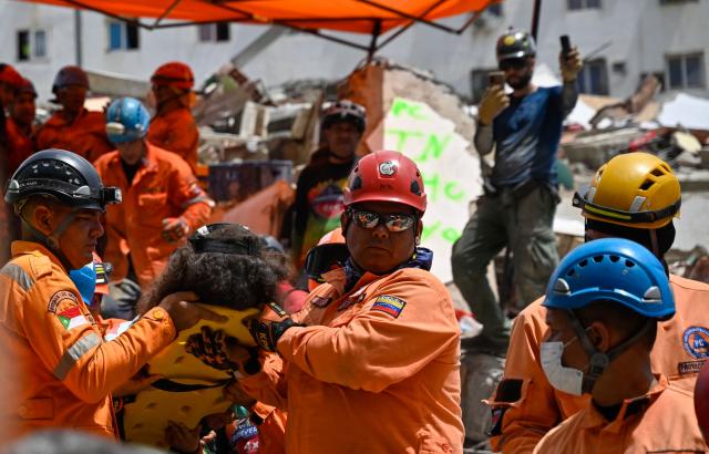 Venezuelan Civil Protection members carry a person on a stretcher at the site of a collapsed building following earthquakes in Caraballeda, La Guaira state, Venezuela, on June 26, 2026. The death toll from two powerful earthquakes that devastated Venezuela earlier this week rose to 920 on June 26, National Assembly President Jorge Rodriguez said. (Photo by Maryorin Mendez / AFP)