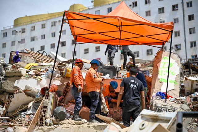 Venezuelan Civil Protection members work at the site of a collapsed building following earthquakes in Caraballeda, La Guaira state, Venezuela, on June 26, 2026. The death toll from two powerful earthquakes that devastated Venezuela earlier this week rose to 920 on June 26, National Assembly President Jorge Rodriguez said. (Photo by Maryorin Mendez / AFP)