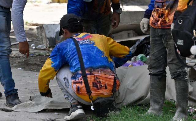 EDITORS NOTE: Graphic content / Volunteers cover the body of a victim with a sheet at the site of collapsed buildings following earthquakes in Caraballeda, La Guaira state, Venezuela, on June 26, 2026. The death toll from two powerful earthquakes that devastated Venezuela earlier this week rose to 920 on June 26, National Assembly President Jorge Rodriguez said. (Photo by Maryorin Mendez / AFP)