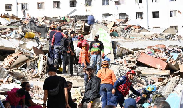 Venezuelan Civil Protection members, firefighters and volunteers work at the site of a collapsed building following earthquakes in Caraballeda, La Guaira state, Venezuela, on June 26, 2026. The death toll from two powerful earthquakes that devastated Venezuela earlier this week rose to 920 on June 26, National Assembly President Jorge Rodriguez said. (Photo by Maryorin Mendez / AFP)