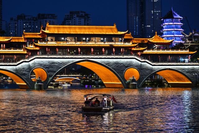 A tourist boat sails on the Jin River past the Anshun Bridge in Chengdu, in China's southwestern Sichuan province on June 26, 2026. (Photo by HECTOR RETAMAL / AFP)