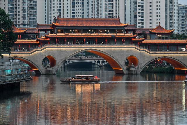 A boat sails past the Anshun Bridge over the Jin River in Chengdu, in China's southwestern Sichuan province on June 26, 2026. (Photo by HECTOR RETAMAL / AFP)