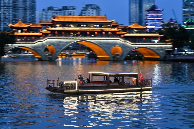 A tourist boat sails past the Anshun Bridge over the Jin River in Chengdu, in China's southwestern Sichuan province on June 26, 2026. (Photo by HECTOR RETAMAL / AFP)